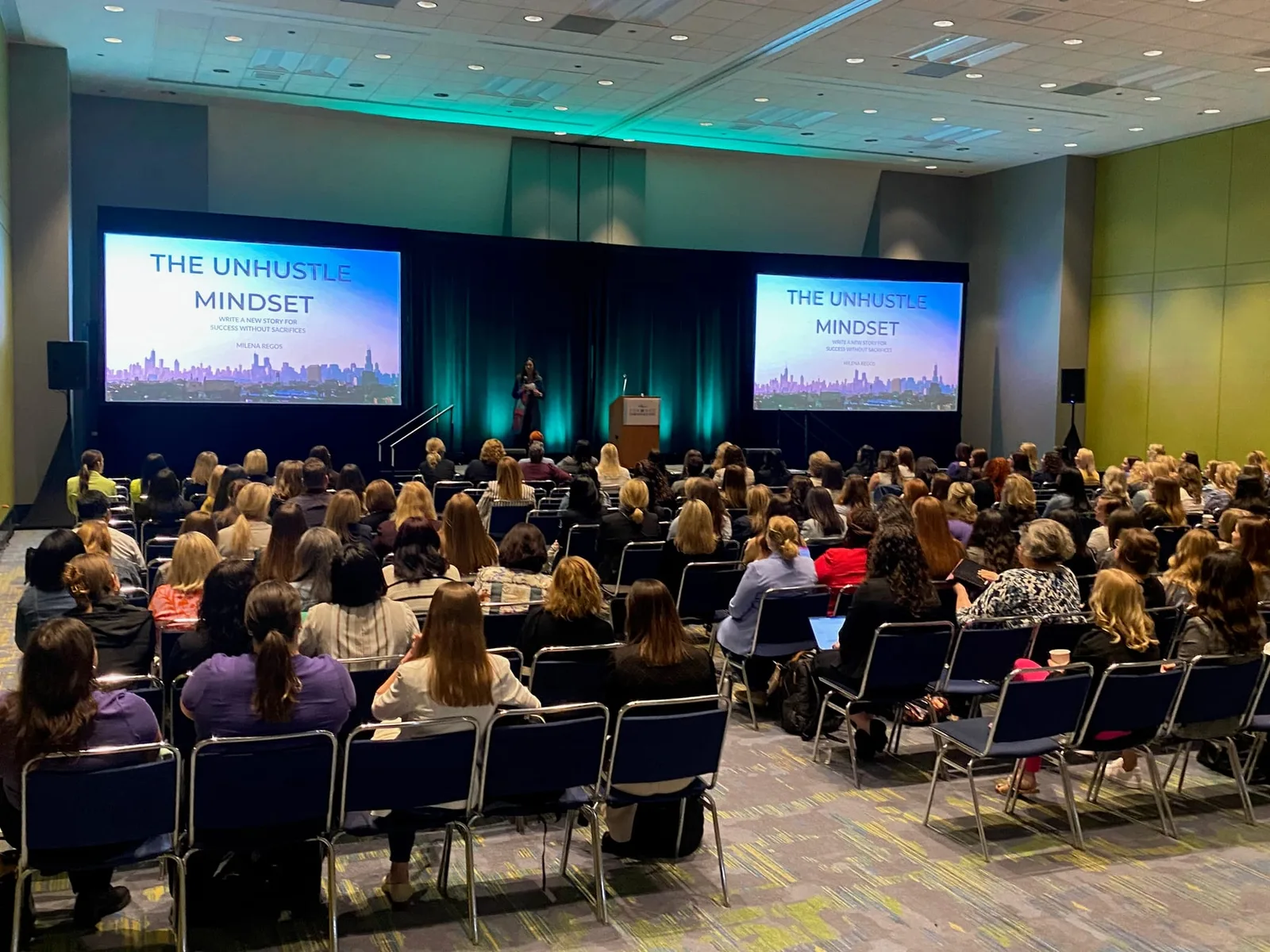 Milena Miteva-Regos delivering The Unhustle Mindset keynote to a full conference ballroom